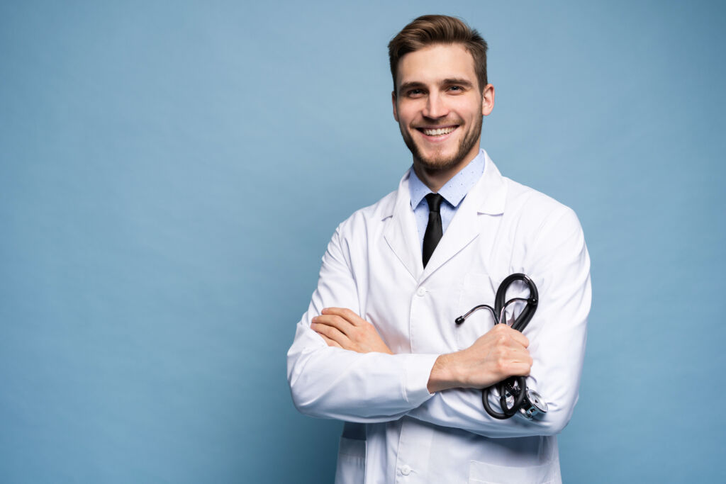 Portrait of confident young medical doctor on blue background.